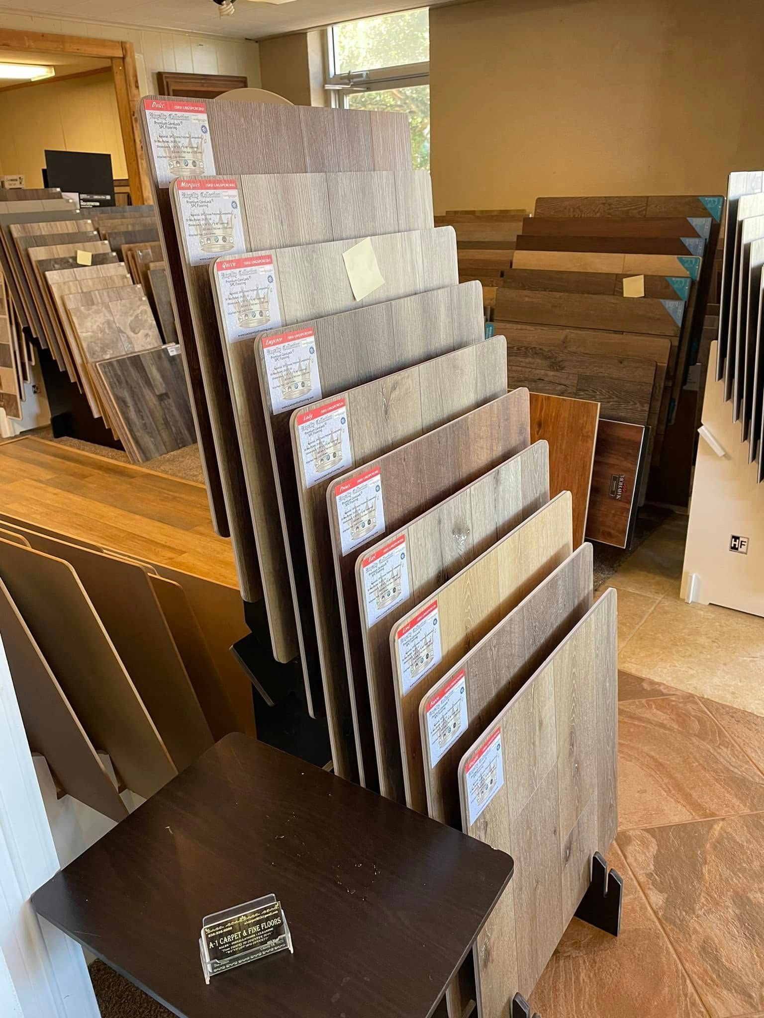 Display of flooring samples in a showroom, with stacked wood and tile boards on racks.