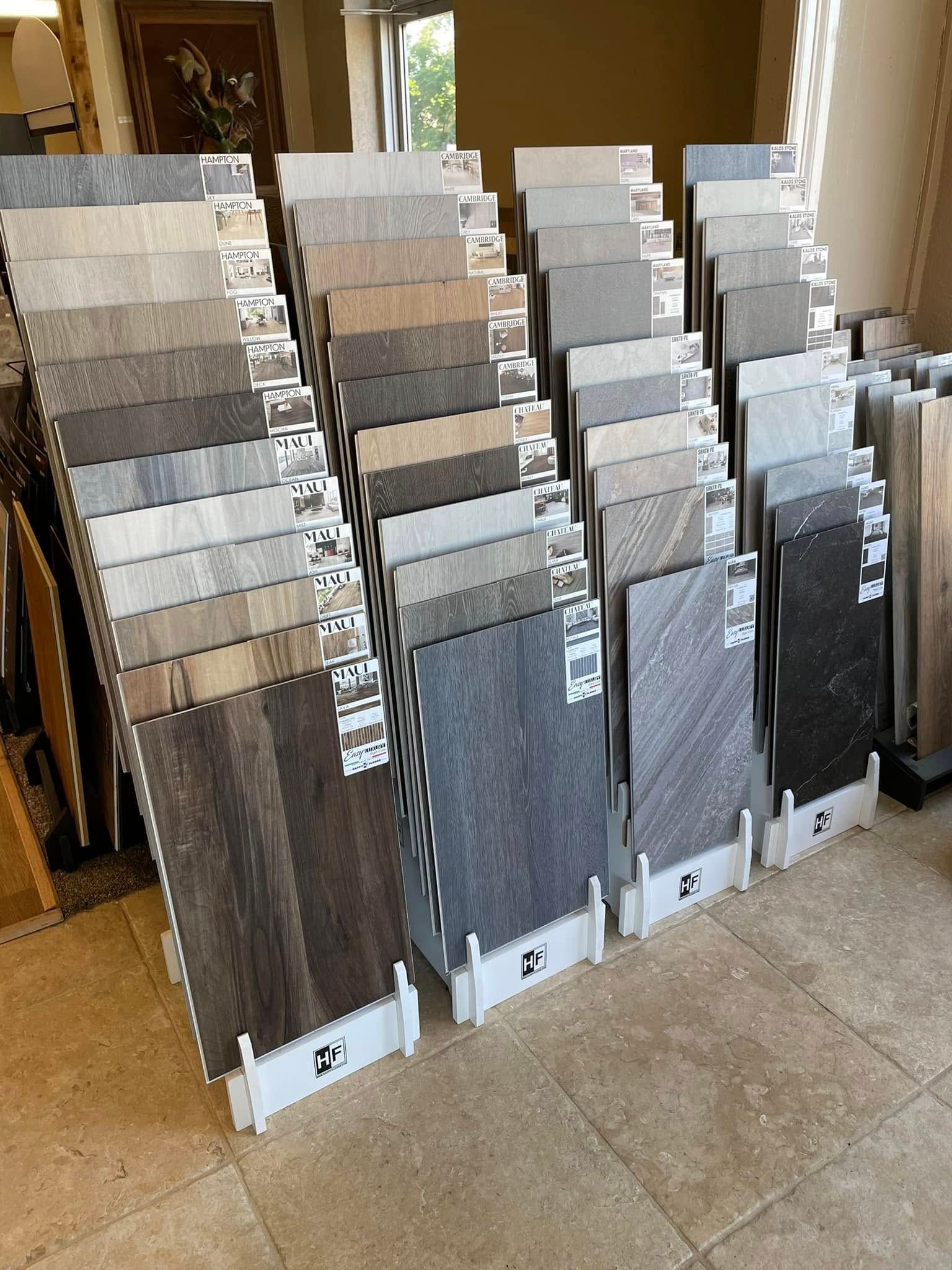 Rows of tile samples displayed on stands in a showroom, in neutral gray and beige tones.