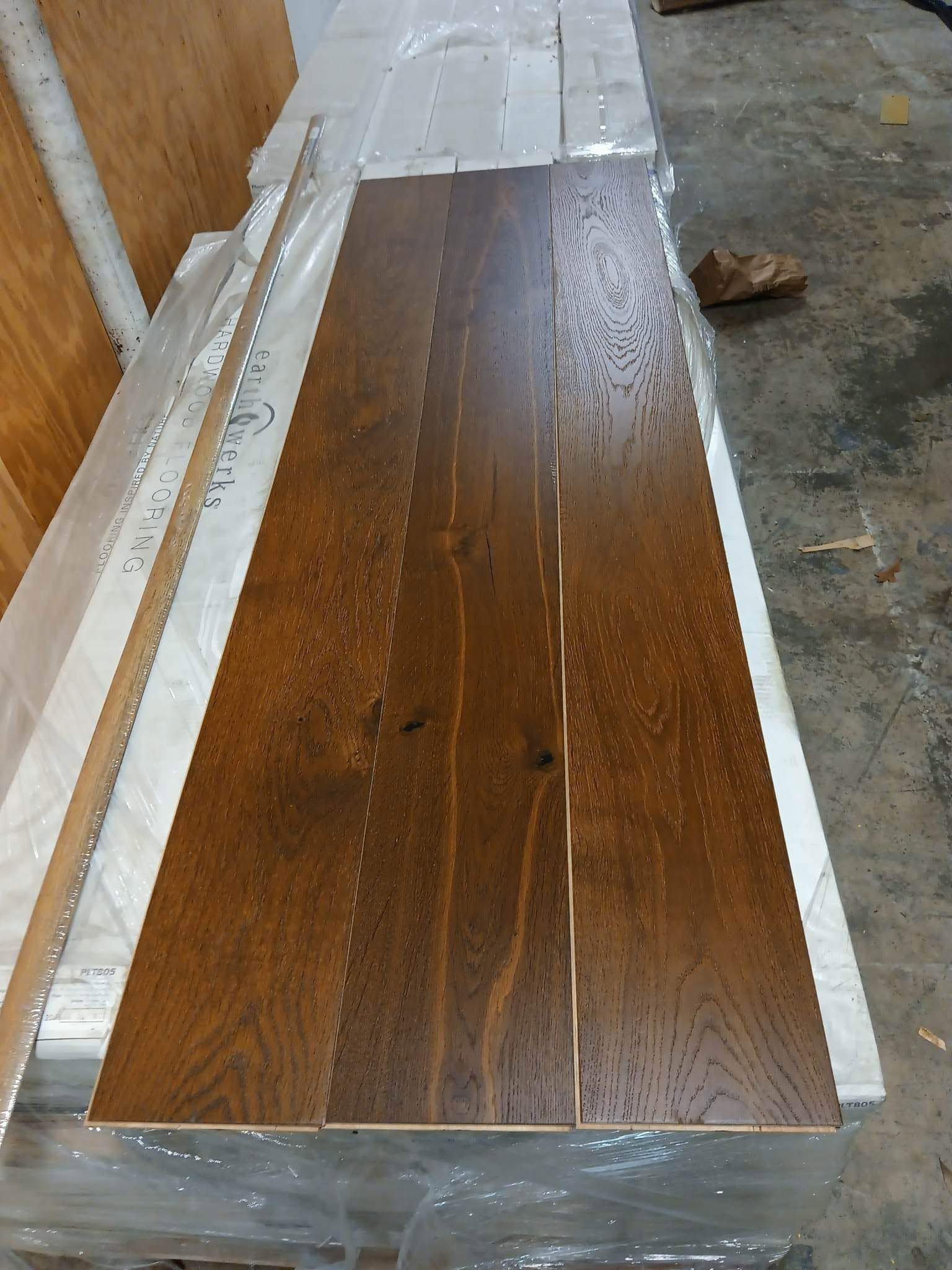 Wrapped dark wood tabletop panels in a workshop, bordered with white tape and plastic.