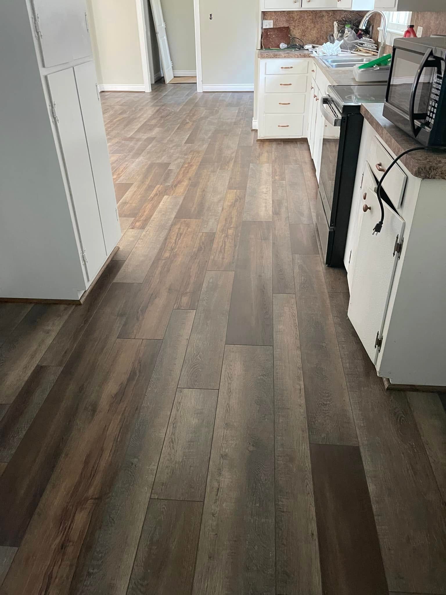 Kitchen floor leading to white cabinets, drawers, and a stove on the right.