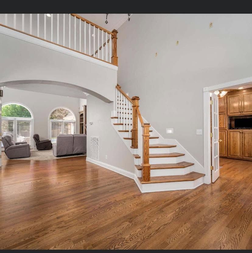 Spacious home interior with hardwood floors, curved staircase, and arched openings to a living room