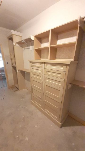 Built-in wooden storage cabinets and shelves in an unfinished closet or laundry room.