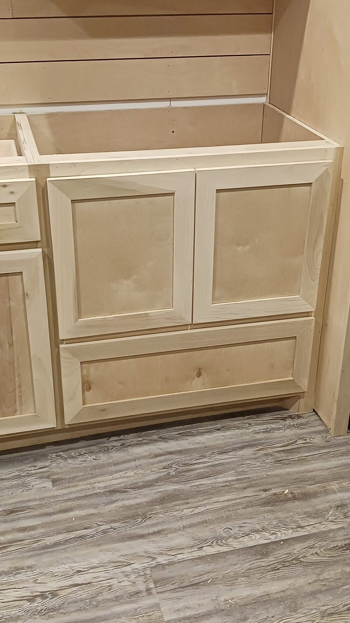 Wooden paneled cabinet under a staircase on a gray carpeted floor