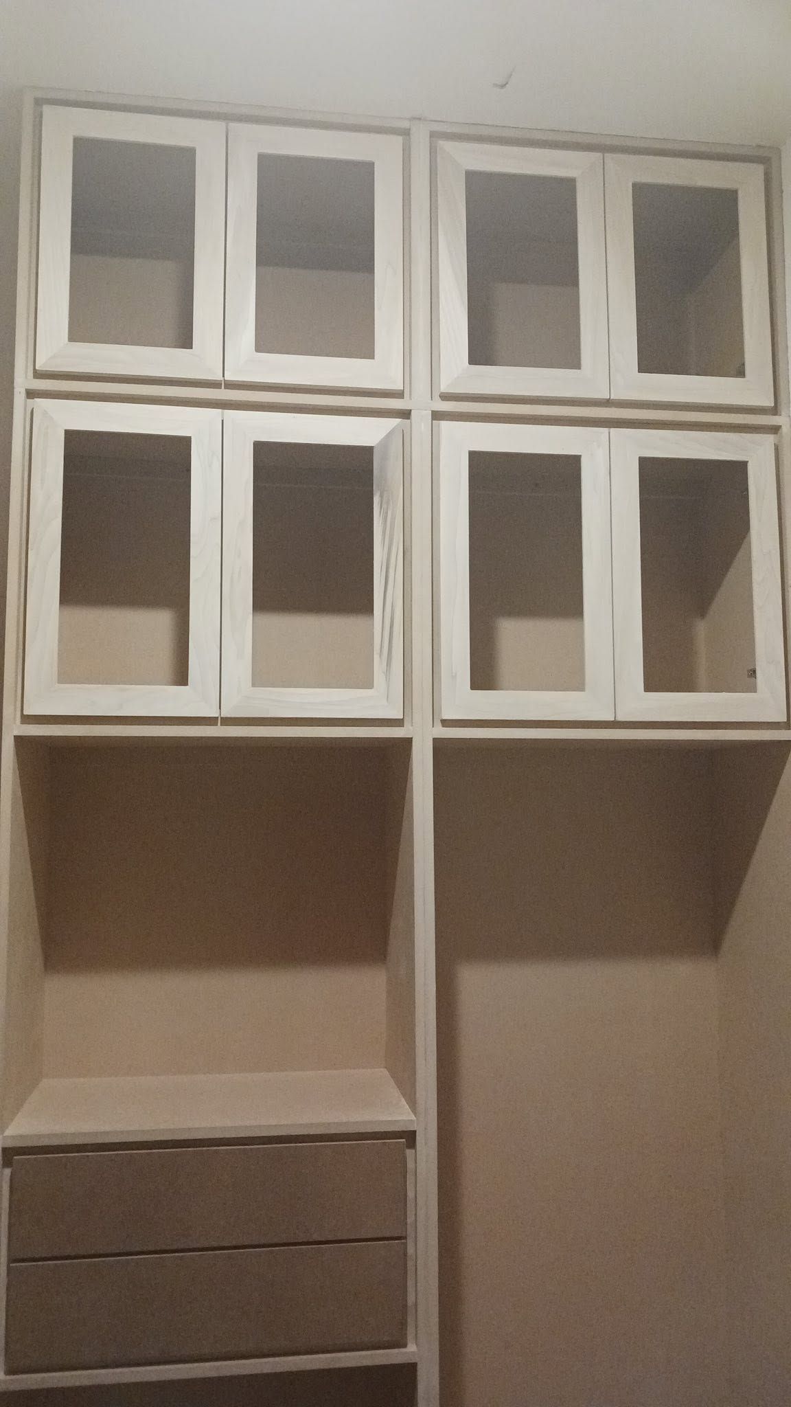 White wall-mounted storage cabinet with glass-front upper doors, open shelves, and drawers below.