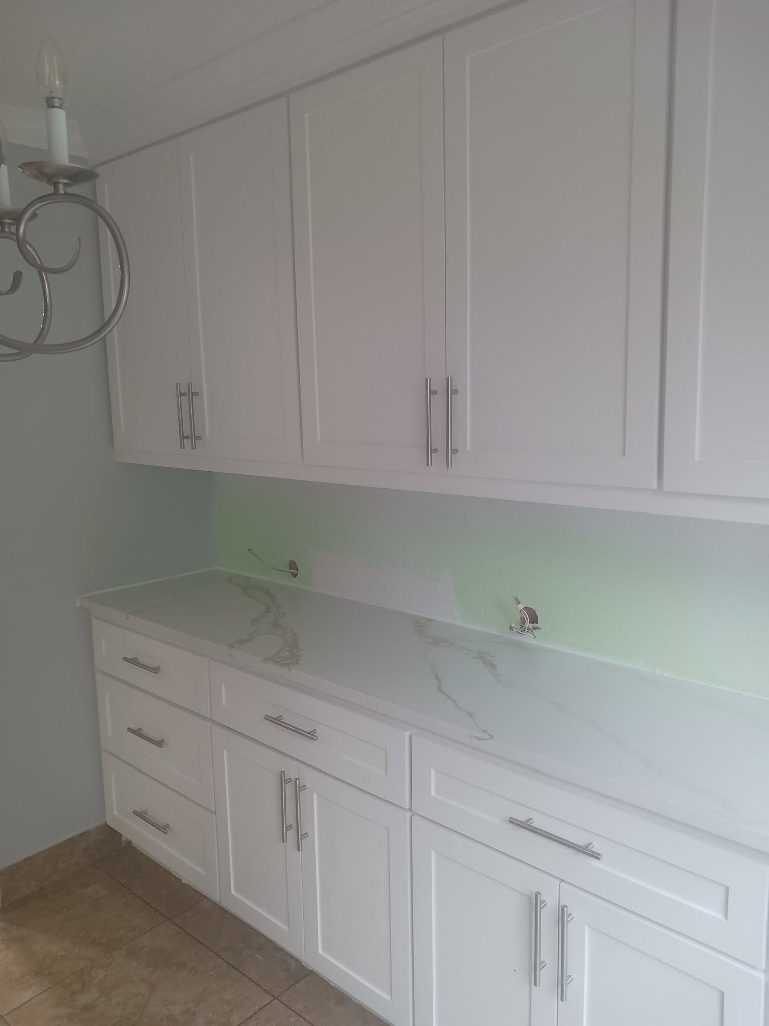 White laundry room with built-in cabinets, marble-look countertop, and light wood floor