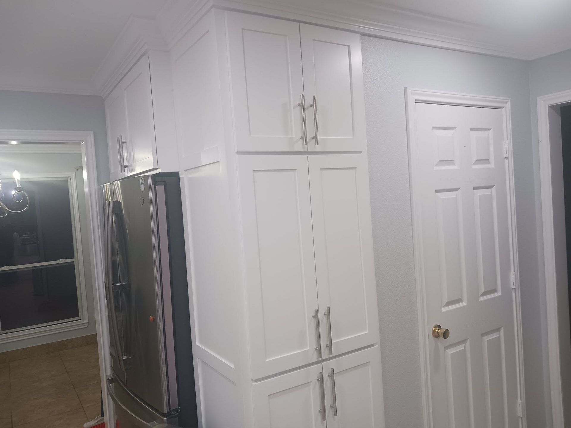 Kitchen with white cabinets, stainless steel refrigerator, and a white door in a bright interior room