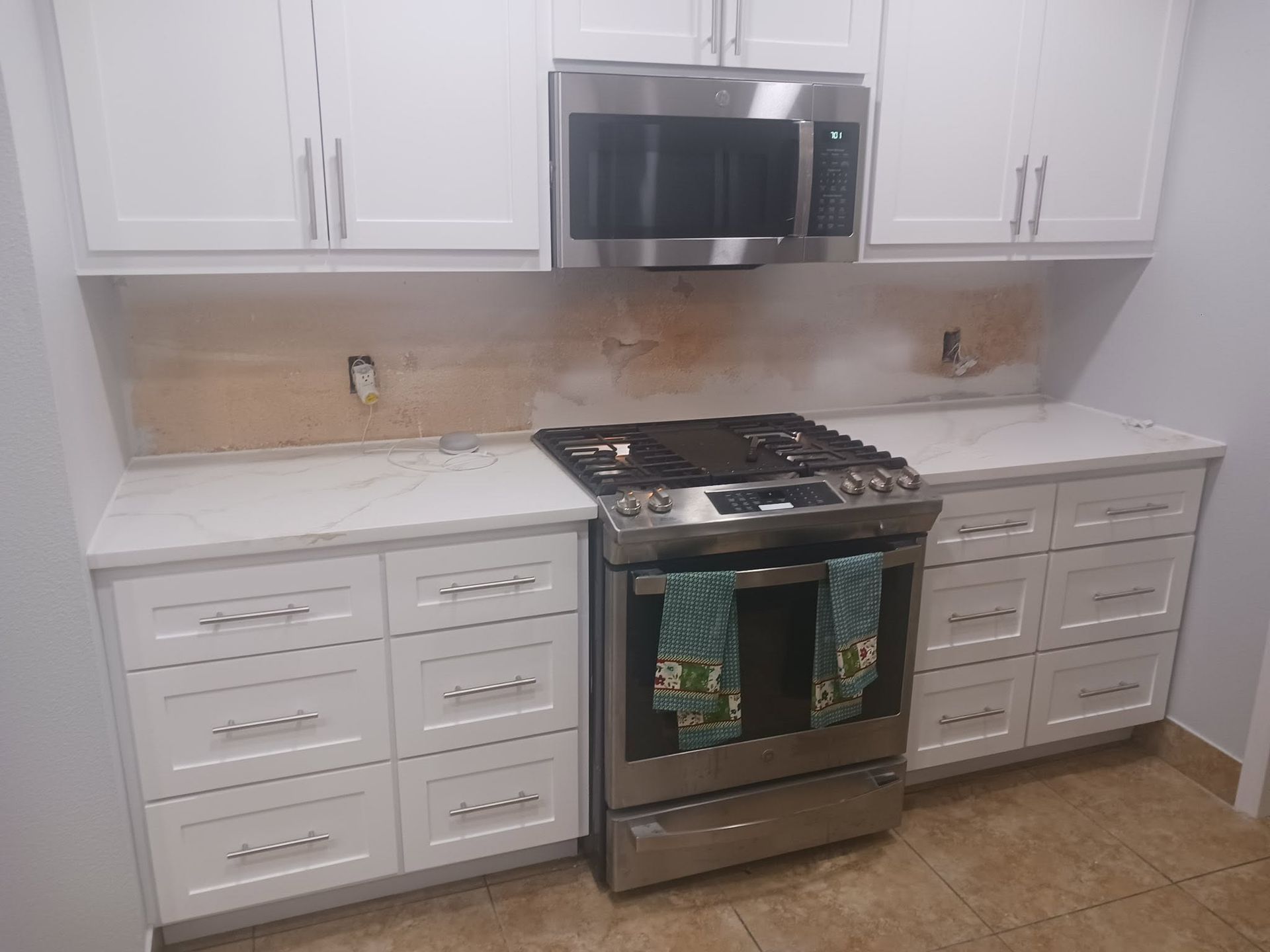 Bright white kitchen with stainless steel stove, microwave, and white cabinets and countertops.