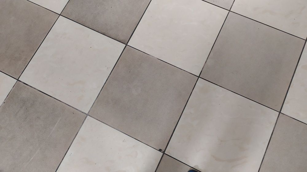 Diagonal view of light gray and beige tiled floor in a checkerboard pattern