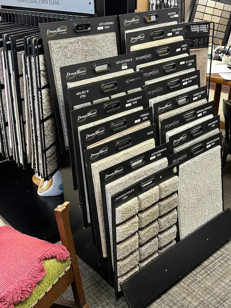 Display racks of carpet and tile samples in a showroom, with black frames and neutral-toned swatches.