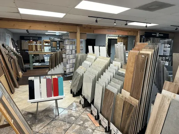 Flooring showroom with rows of carpet and tile samples displayed under bright ceiling lights
