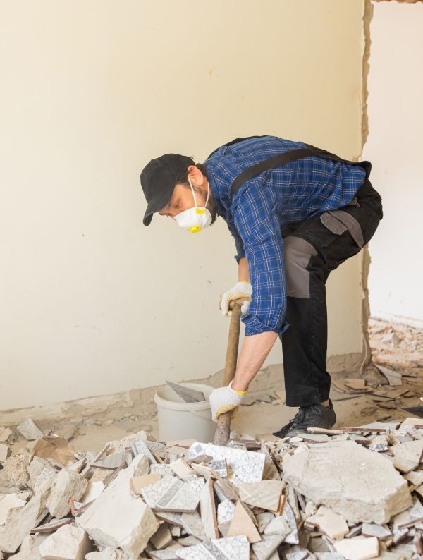 A man wearing a mask and gloves is working on a pile of concrete.