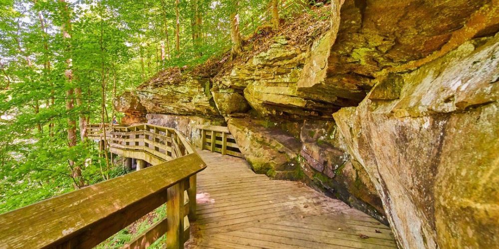 A wooden walkway leading to a cave in the woods.