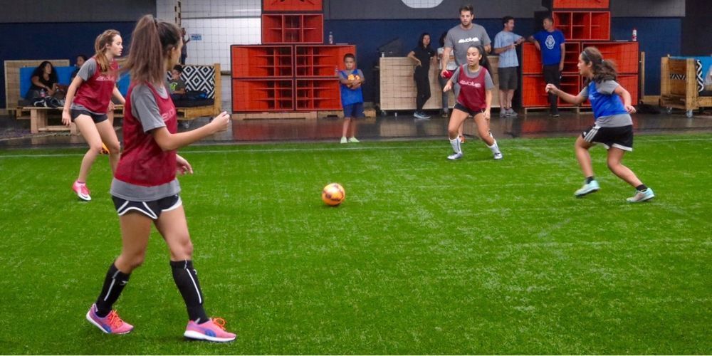 A group of young girls are playing soccer on a field.
