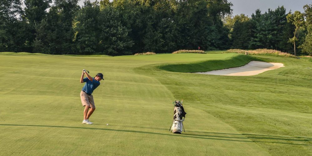 A man is swinging a golf club on a golf course.