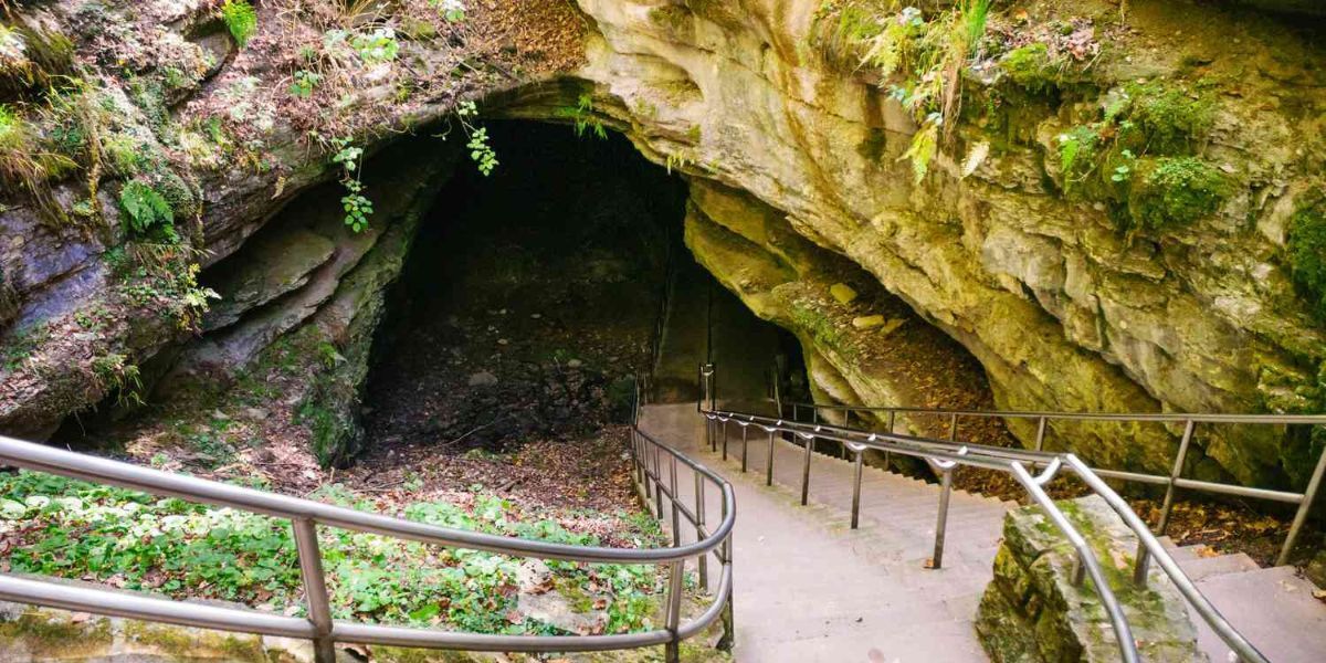 A cave with stairs leading up to it and a railing.
