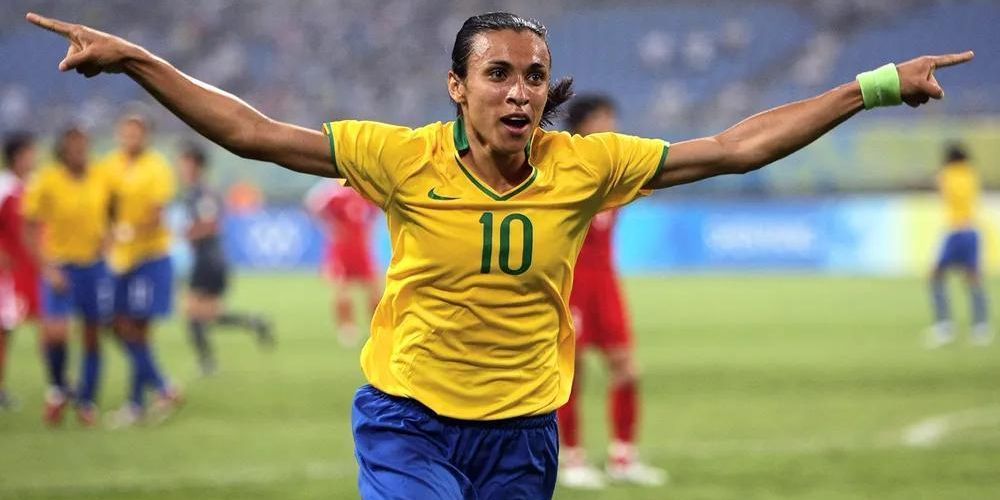 A soccer player wearing a yellow shirt with the number 10 on it is celebrating a goal.