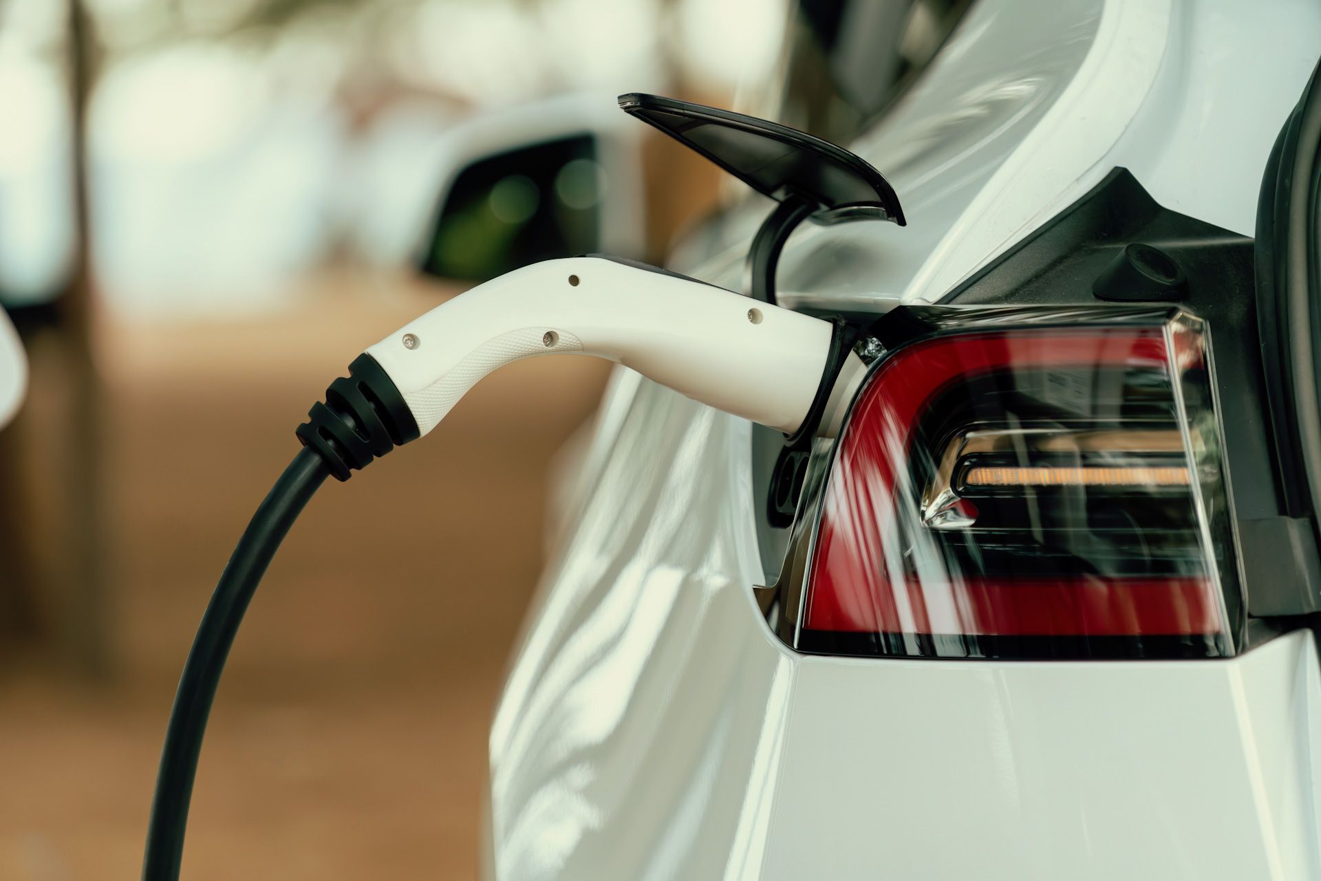 A white electric car is being charged at a charging station.