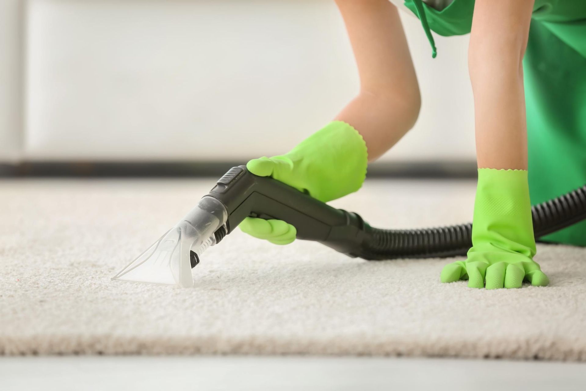 A woman is cleaning a carpet with a vacuum cleaner.
