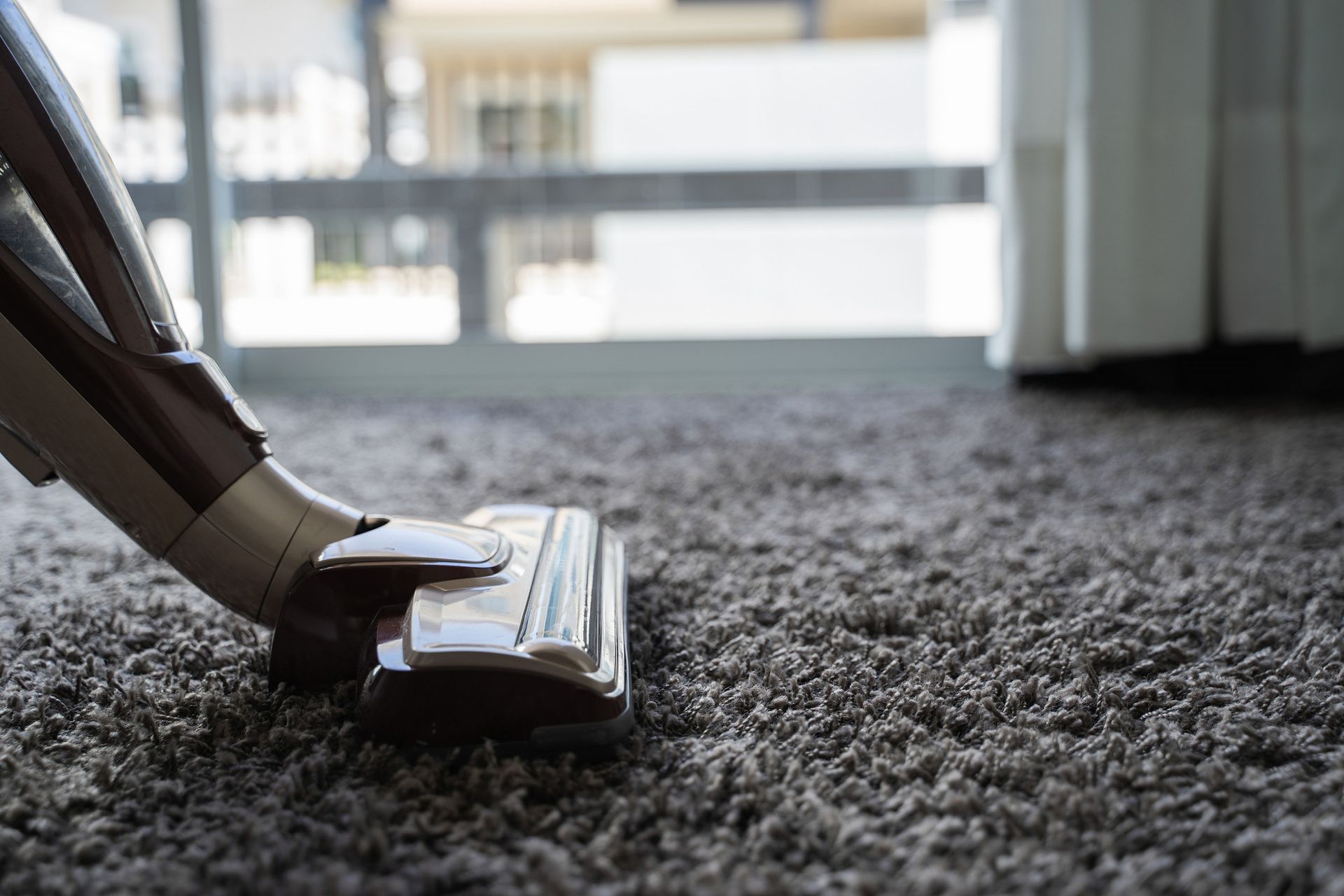 A vacuum cleaner is cleaning a carpet in a living room.