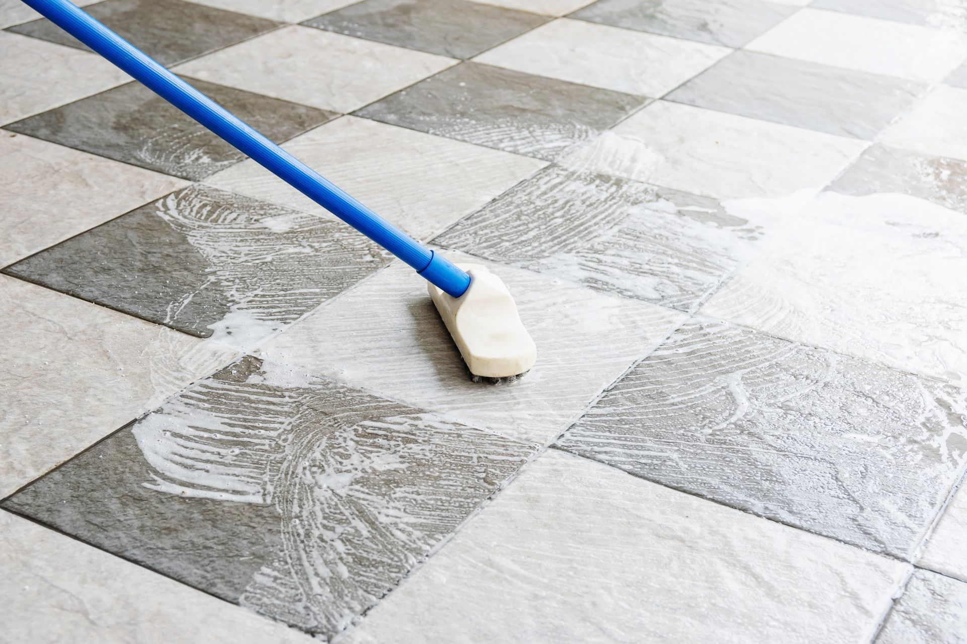 A person is cleaning a tiled floor with a mop.