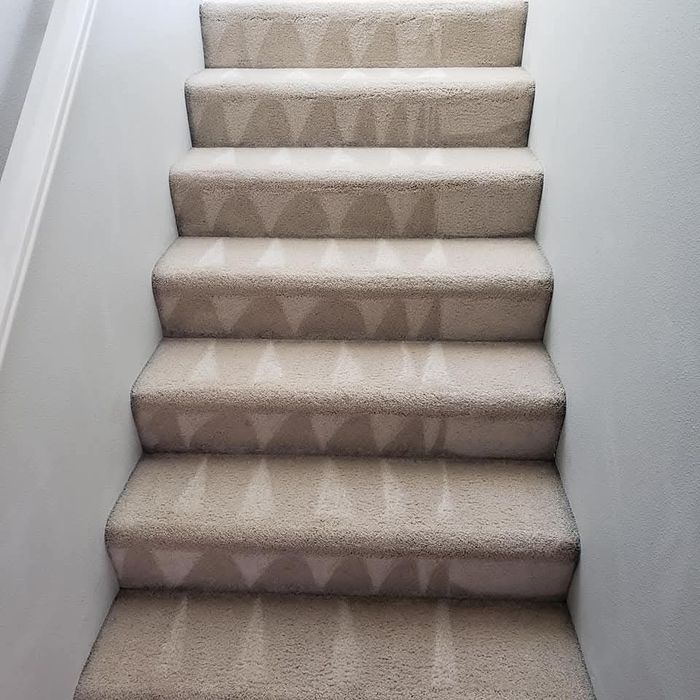 Carpeted staircase with beige-patterned runner and white walls leading upward in Rock Castle