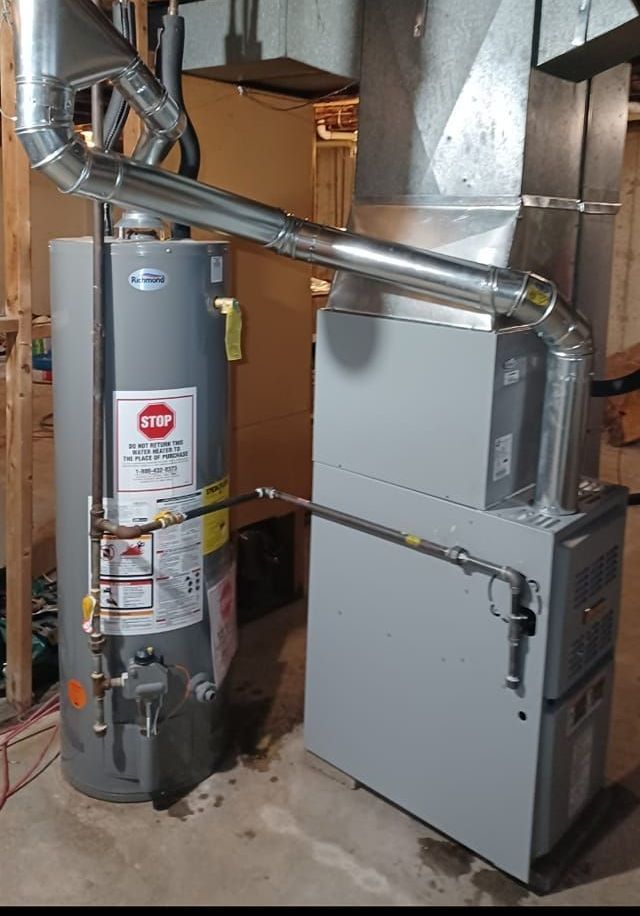 Water heater and furnace installed in a basement. Silver metal pipes connect the appliances.