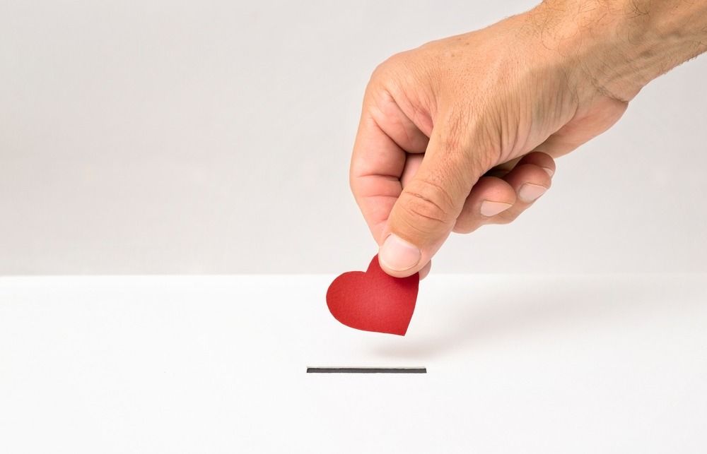 Hand placing red heart into slot.
