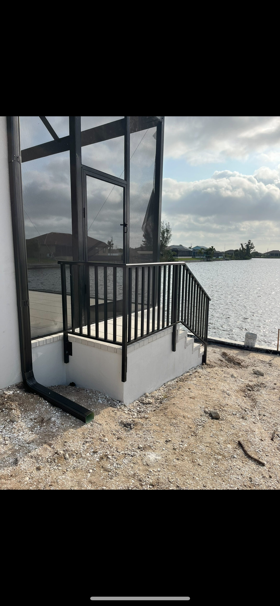 A staircase leading up to a screened in porch overlooking a body of water.