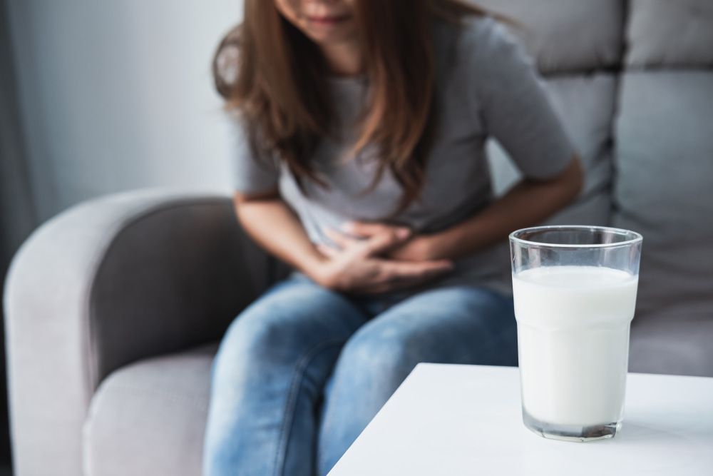 A Woman Is Sitting On A Couch With A Glass Of Milk On A Table — Naturopath Australia In Mermaid Beach, QLD