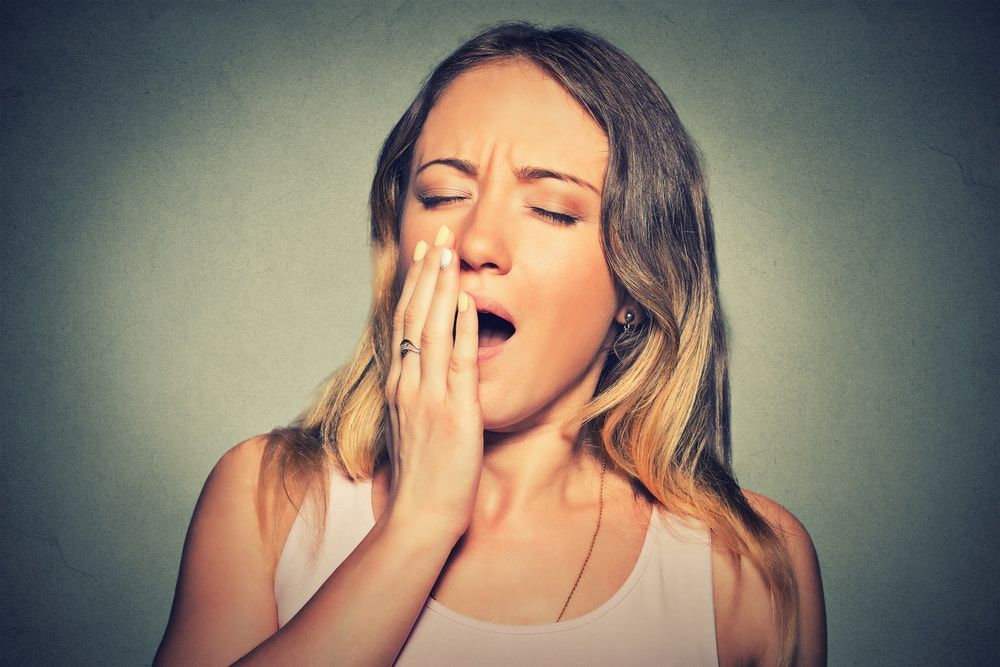 A Woman Is Yawning With Her Hand Over Her Mouth — Naturopath Australia In Byron Bay, NSW