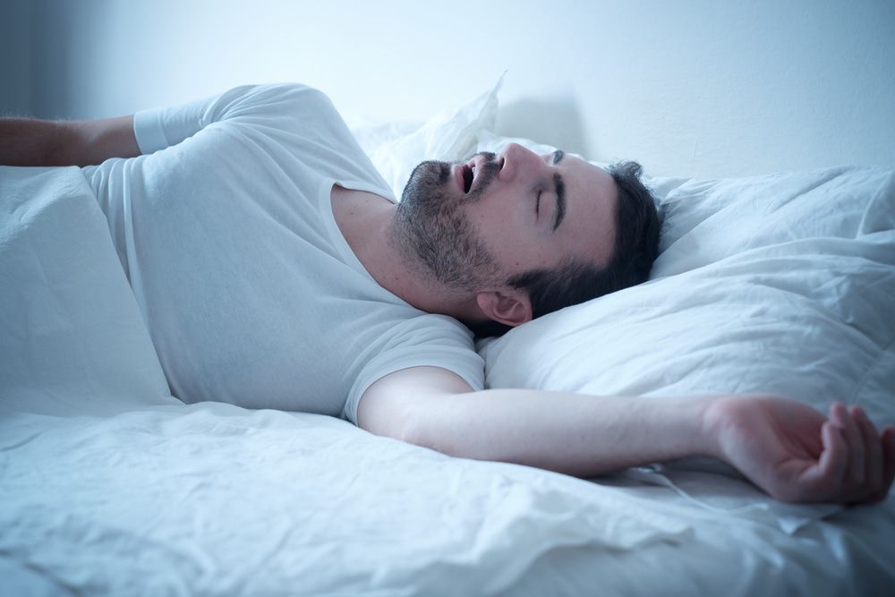 A Man Is Sleeping On A Bed With His Mouth Open — Naturopath Australia In Mermaid Beach, QLD