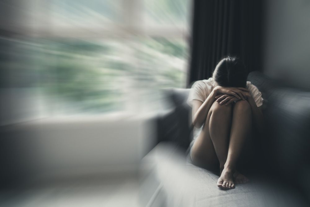 A Woman Is Sitting On A Couch In Front Of A Window — Naturopath Australia In Mermaid Beach, QLD