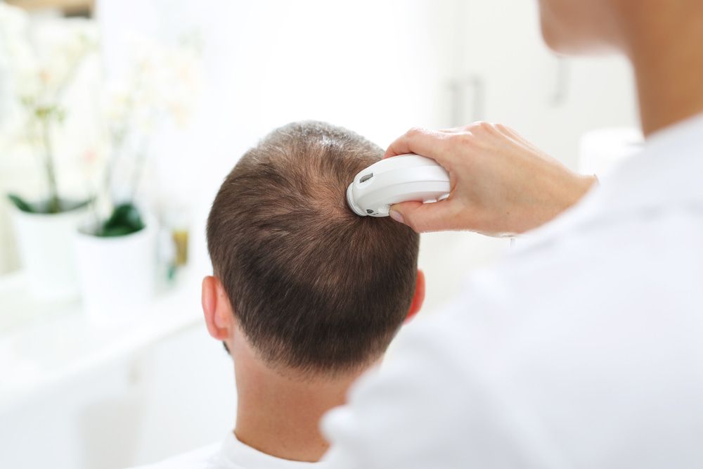 A Man Is Getting His Hair Examined — Naturopath Australia In Byron Bay, NSW
