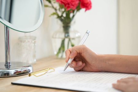 A Person Is Writing On A Piece Of Paper With A Pen — Naturopath Australia In Mermaid Beach, QLD