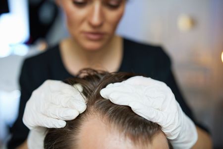A Woman Is Examining A Man 's Hair With White Gloves — Naturopath Australia In Mermaid Beach, QLD