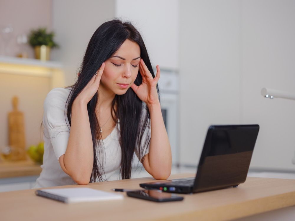 A Woman Is Sitting In Front Of A Laptop With Her Hands On Her Head — Naturopath Australia In Mermaid Beach, QLD