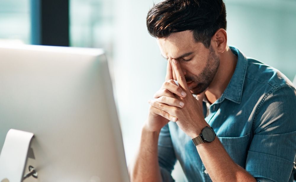 A Man Sitting In Front Of A Computer With His Hands On His Face — Naturopath Australia In Mermaid Beach, QLD
