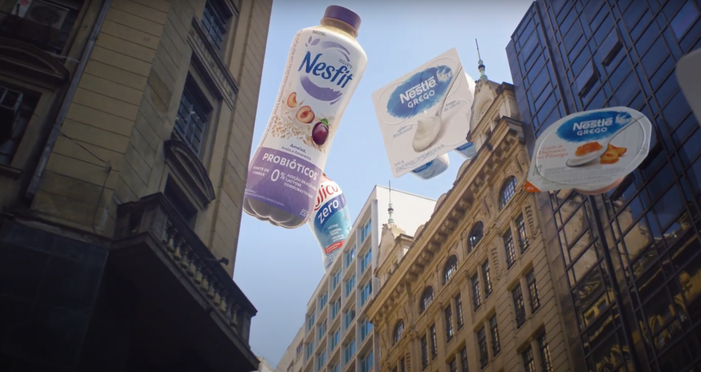 Uma garrafa de iogurte nestlé está flutuando no ar entre dois prédios.