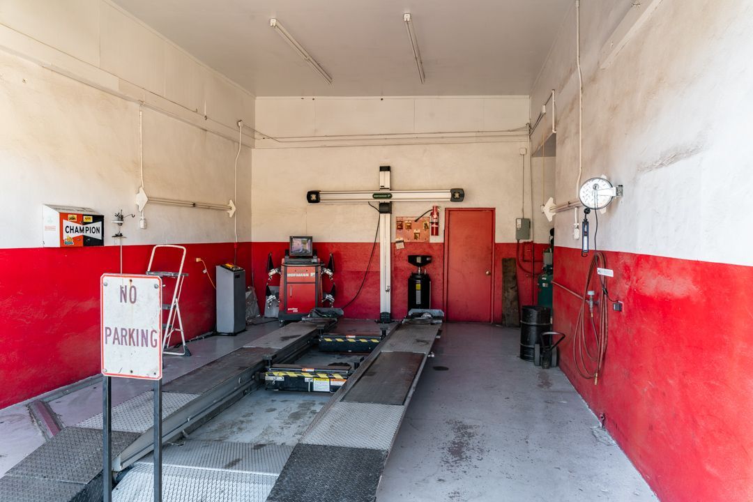 Auto repair garage interior with a car lift, tools, and red lower walls