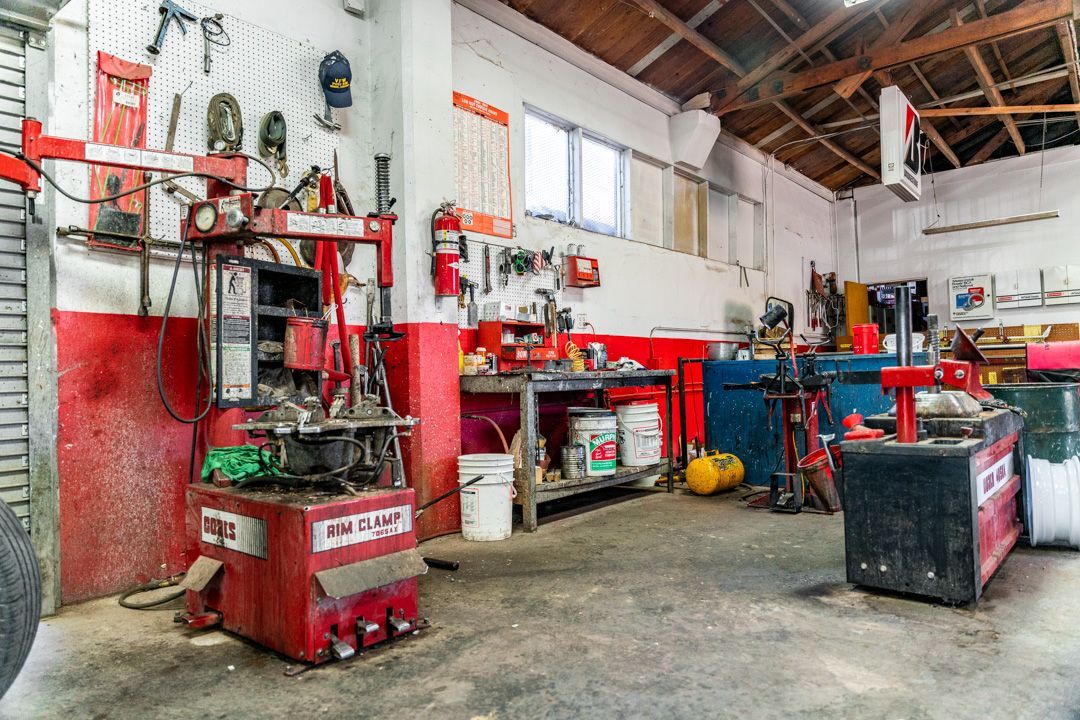 Industrial workshop with red machinery, tools, and a high ceiling in a cluttered garage-like space