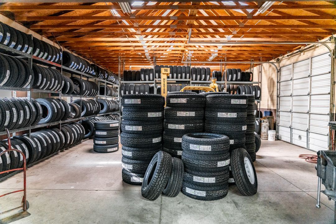 Tire shop warehouse with stacked black tires and rims under a wooden roof