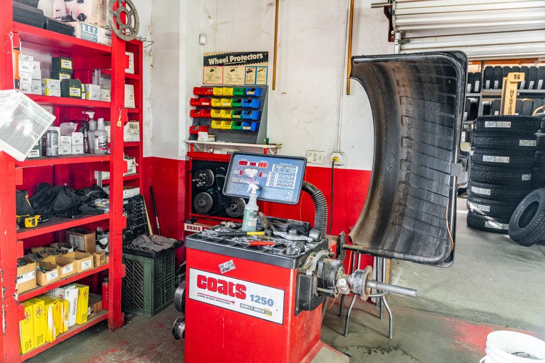 Auto repair shop with red tool cabinets, computer workstation, and a car tire on a lift