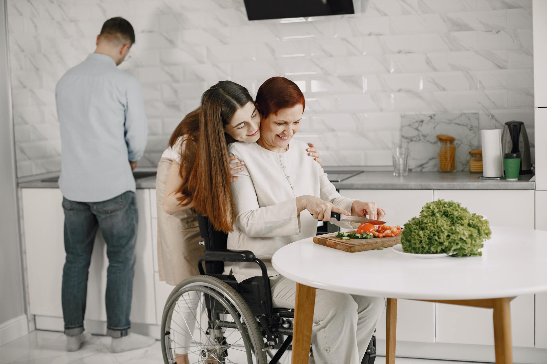 A woman in a wheelchair is sitting at a table with a man and a woman.