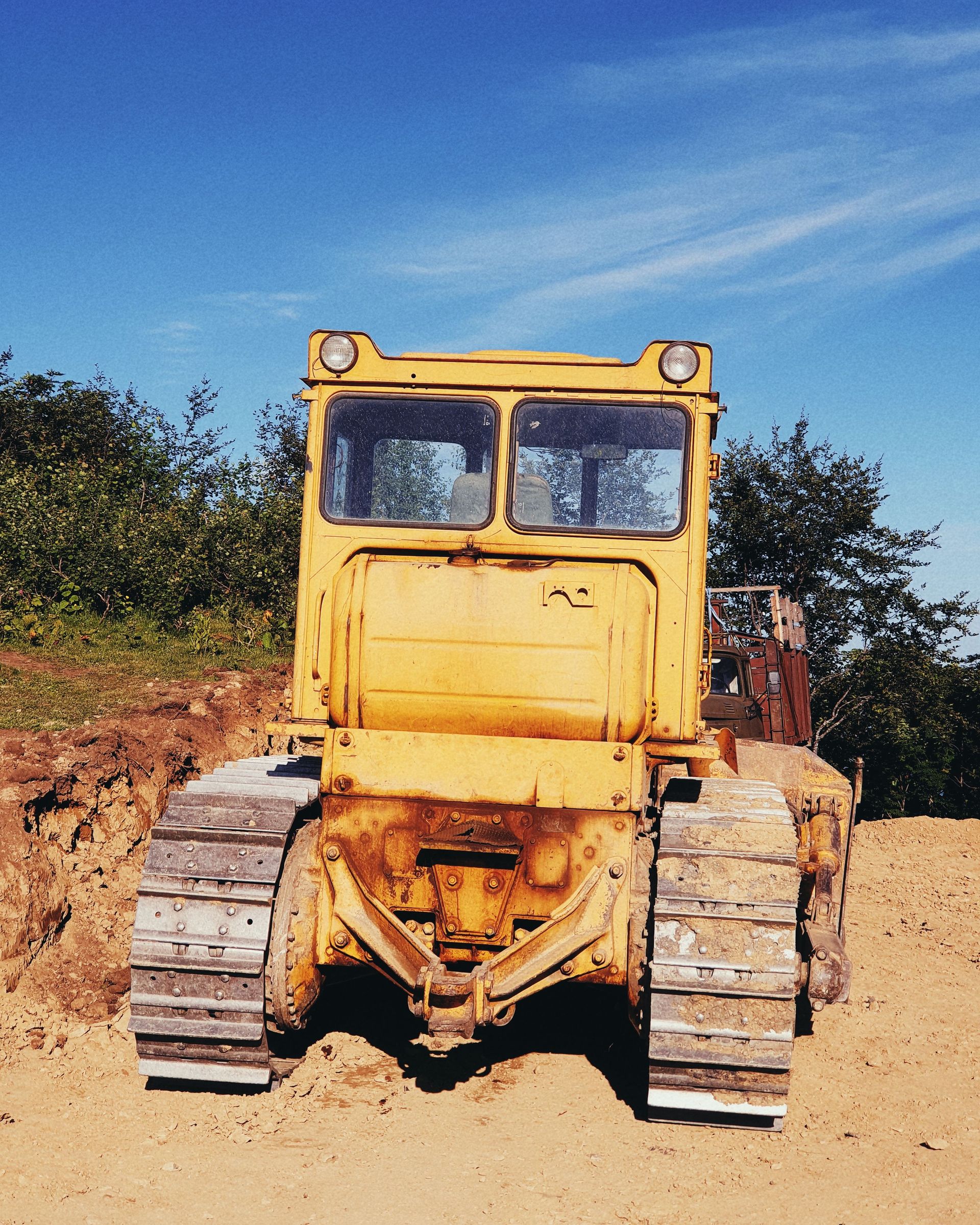 Yellow bulldozer on a dirt site under a blue sky