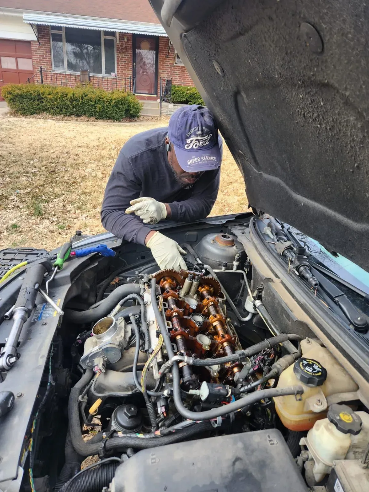 side view of man repairing bonet | Strike Force Mobile Mechanic llc
