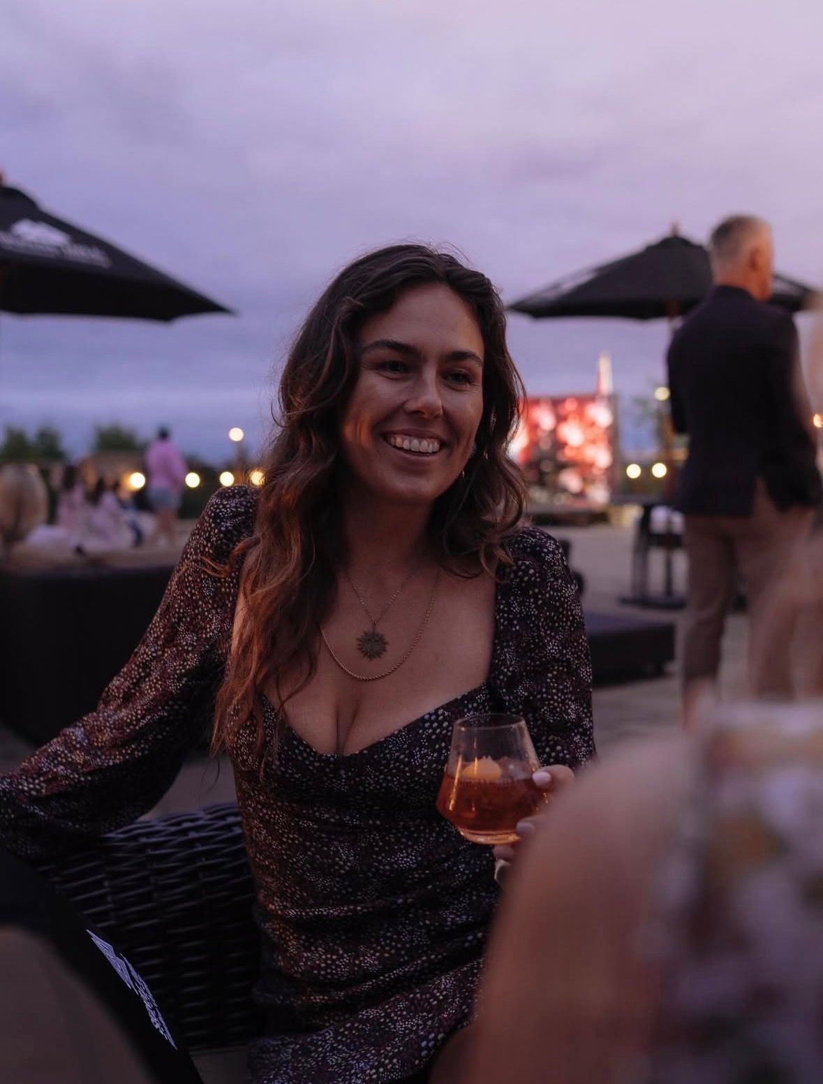 An attendee at the Altitude conference networking reception, smiling and holding a drink in a relaxed, upscale outdoor setting.