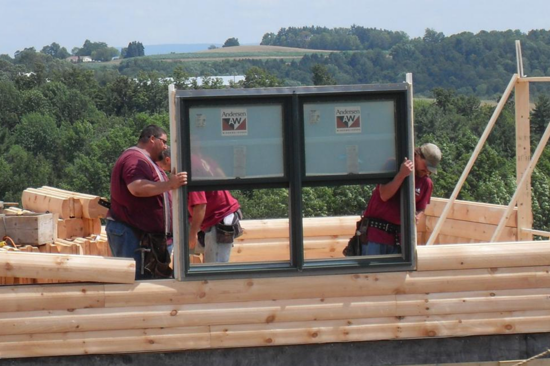A group of men are installing a window in a log cabin