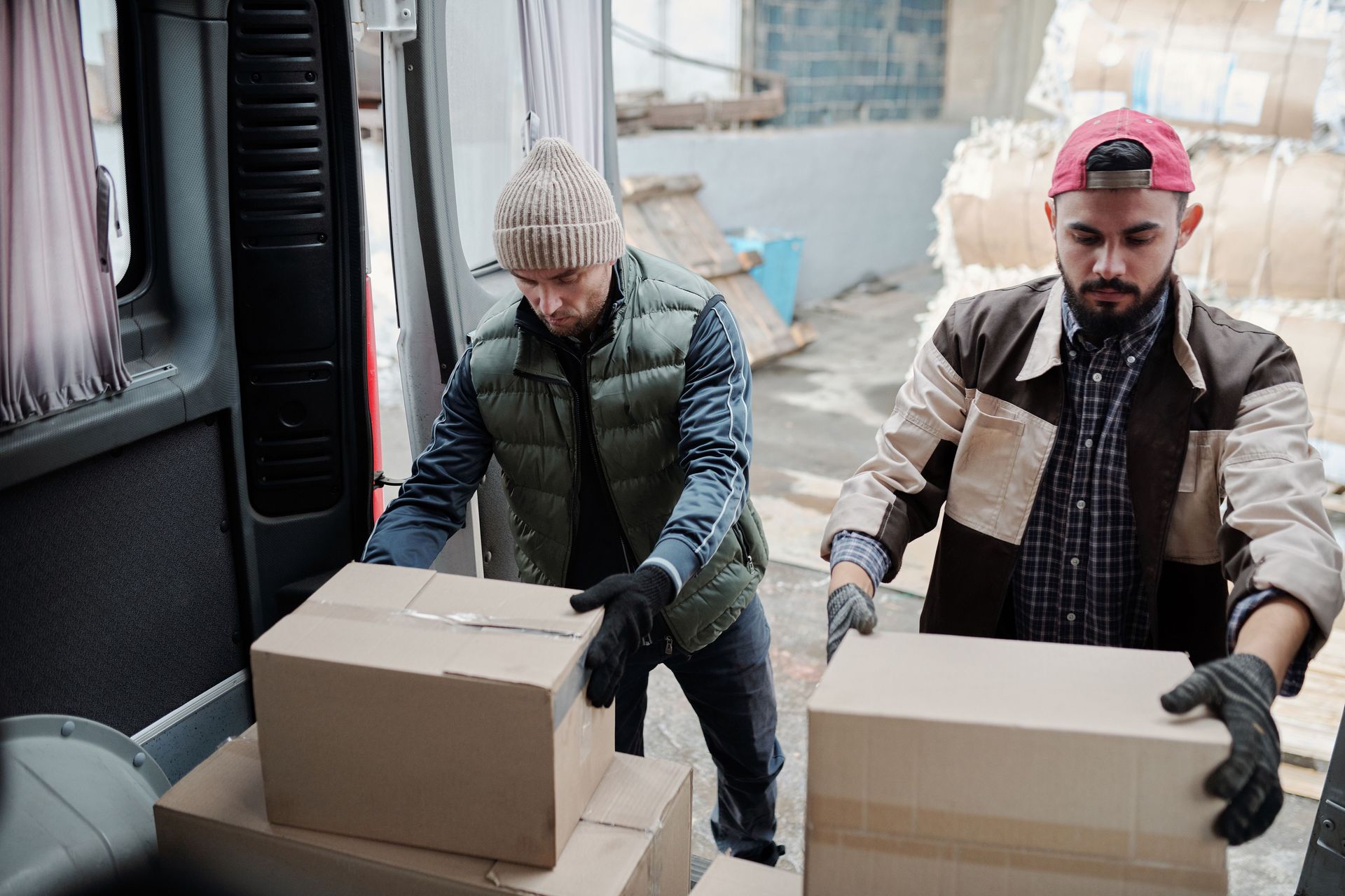 Two men stacking boxes in the back of a vehicle