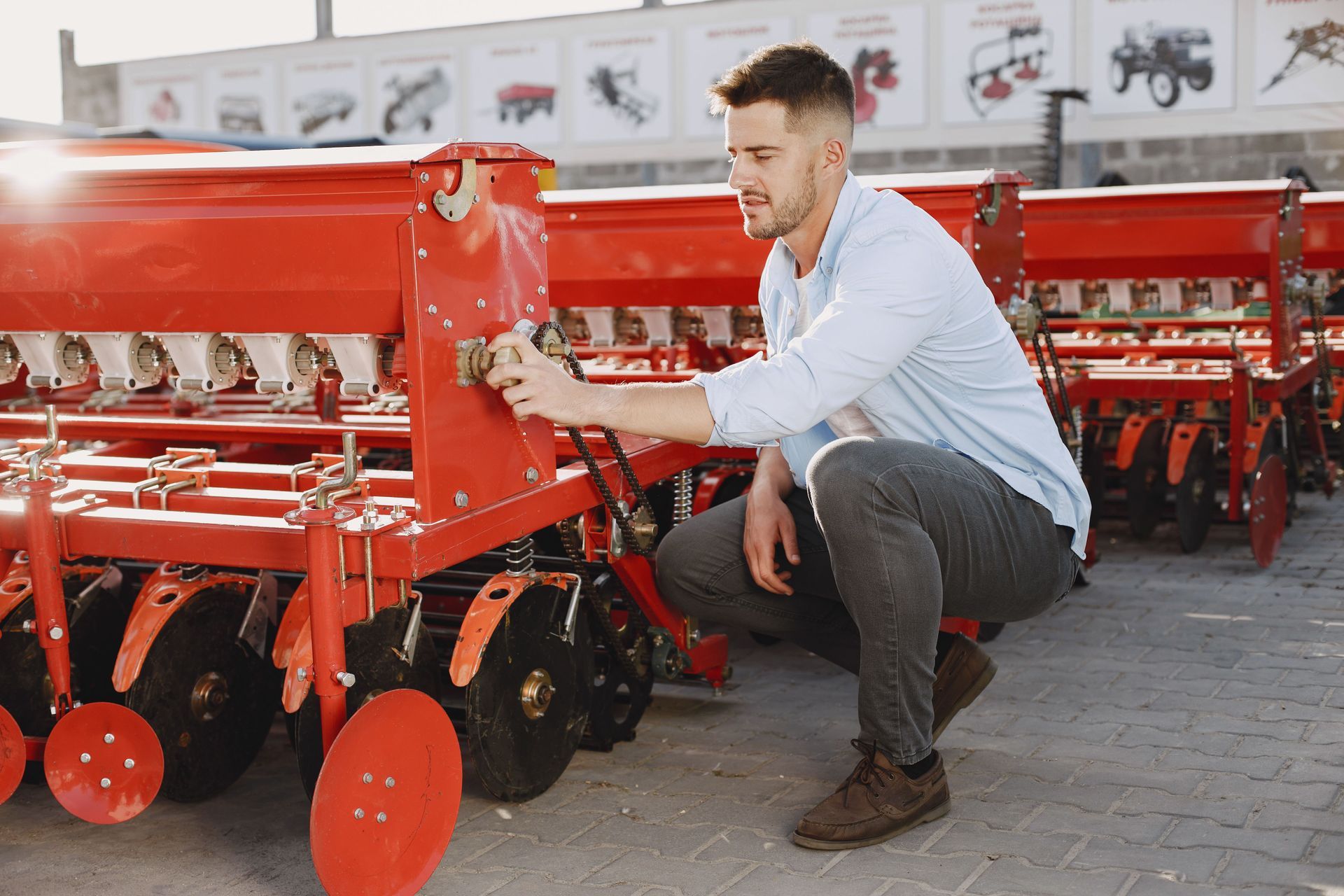 A person checking on red farming equipment.