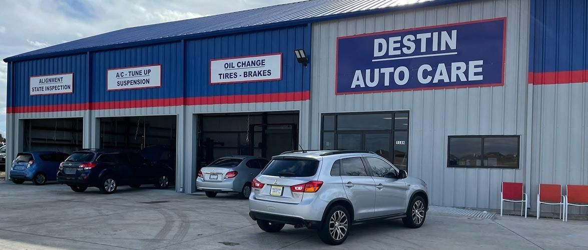 Destin Auto Care shop with cars parked outside. Blue and red building.